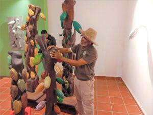 Cayuco junto a una de sus obras de cacao perteneciente a su exposición El fin último de las cosas.